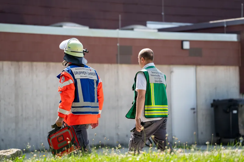 Gruppenführer von Feuerwehr und DRK im Gespräch vor einer Halle