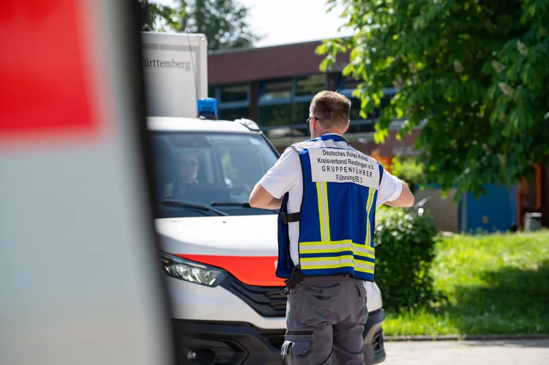 Gruppenführer des DRK neben dem Einsatzfahrzeug