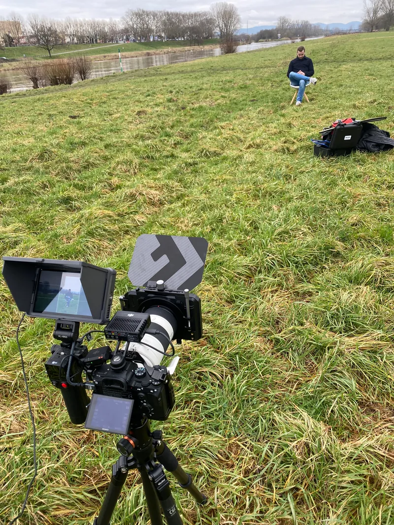 Kamera mit Monitor auf dem Stativ bei einem Interview auf der Wiese