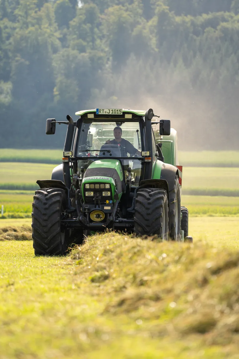 Traktor fährt frontal durchs Heu