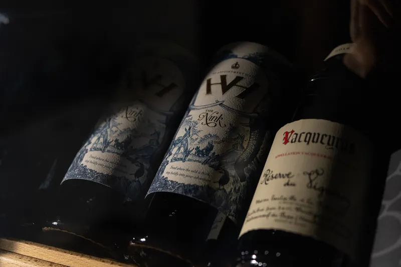 Alte Weinflaschen mit verzierten Etiketten im dunklen Regal